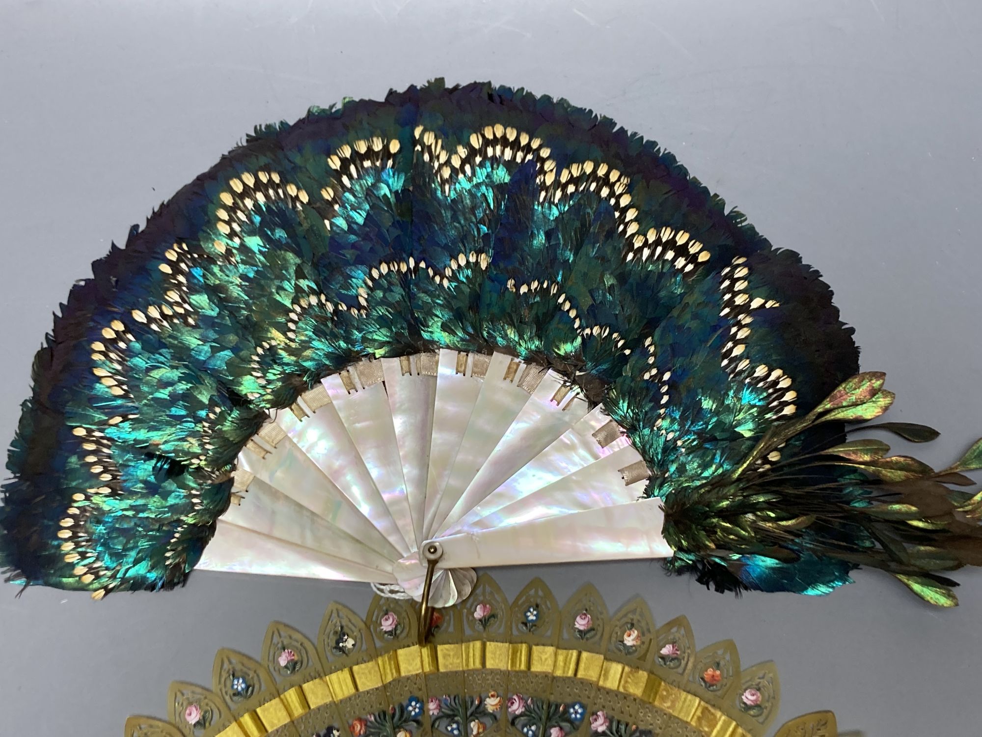 An early 20th century peacock? feather and mother of pearl fan and an early 19th century French painted horn brise fan